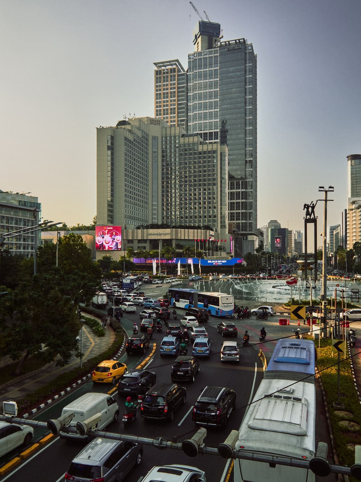 Traffic circling Bundaran HI at dusk, Jakarta's central business district